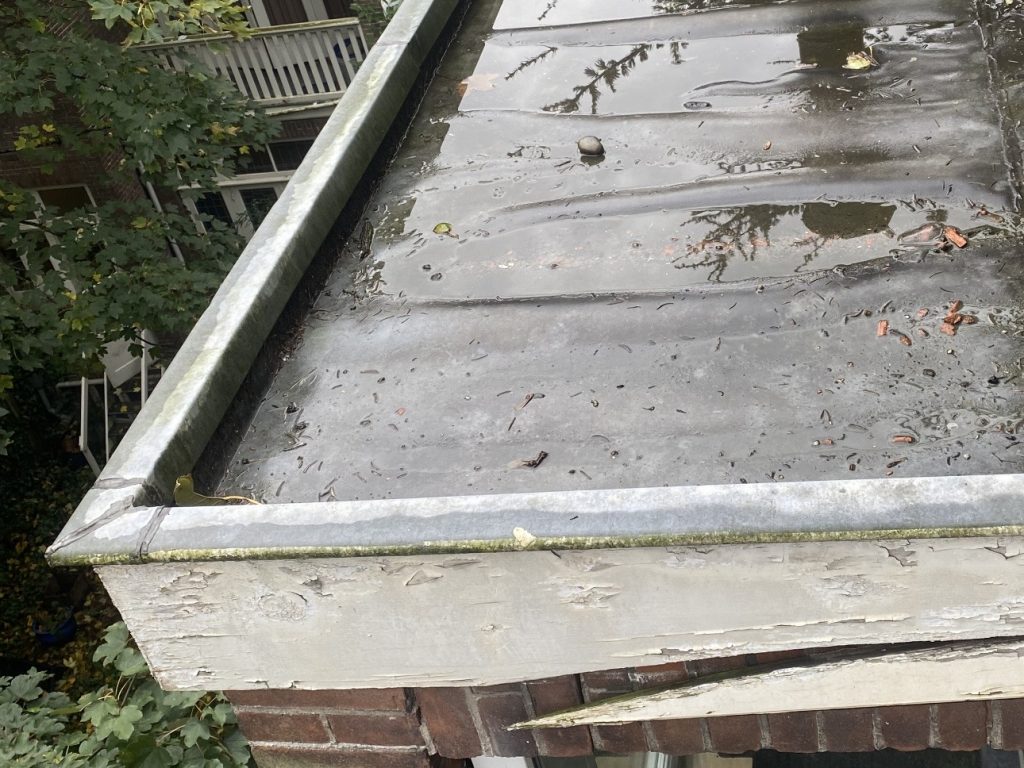 Verouderde zinken dak en verrotte boeidelen