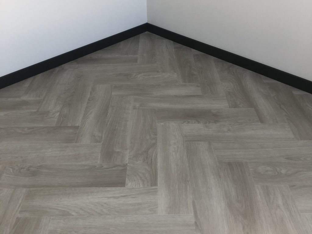 Grijze plak pvc vloer met zwarte hoge plinten